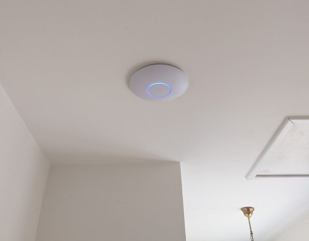 Vente, installation et configuration d'une borne Wi-Fi Ubiquiti au plafond pour améliorer la couverture du réseau sans fil, par JOUVE SCF.