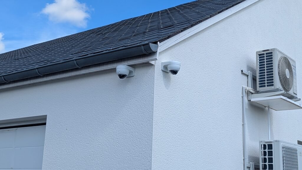 Deux caméras de vidéosurveillance extérieures Dahua installées sous toiture, de chaque côté de l’angle d’un bâtiment, par JOUVE SCF.